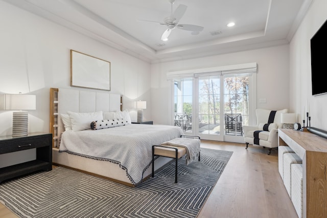 bedroom featuring access to exterior, a tray ceiling, recessed lighting, a ceiling fan, and wood finished floors