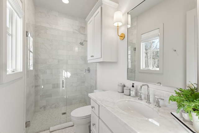 bathroom with a stall shower, vanity, and toilet