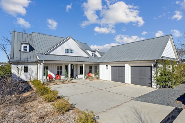 modern farmhouse featuring a garage, driveway, metal roof, a standing seam roof, and a porch