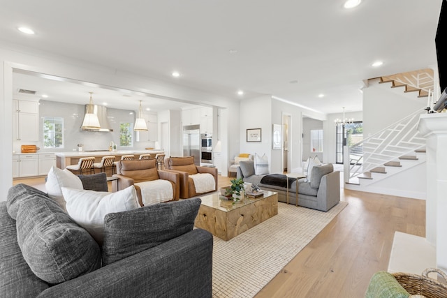 living room with stairs, light wood-type flooring, a chandelier, and recessed lighting