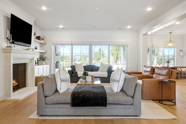 living room featuring light wood finished floors, plenty of natural light, and ornamental molding