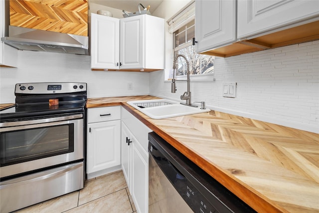 kitchen featuring decorative backsplash, wall chimney exhaust hood, butcher block counters, appliances with stainless steel finishes, and a sink