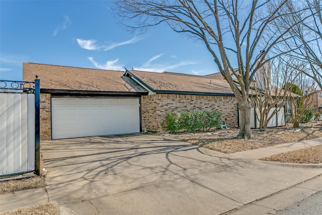 view of front of house featuring driveway, an attached garage, a shingled roof, and brick siding