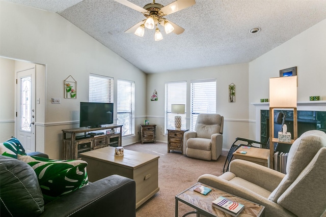 living room featuring lofted ceiling, a textured ceiling, a ceiling fan, and light colored carpet