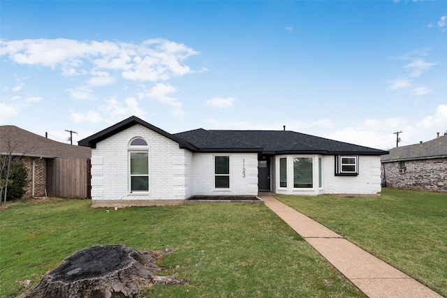 ranch-style house with brick siding, a front lawn, and a shingled roof