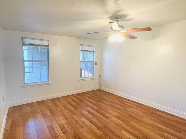 unfurnished room with a textured ceiling, light wood-type flooring, a ceiling fan, and baseboards