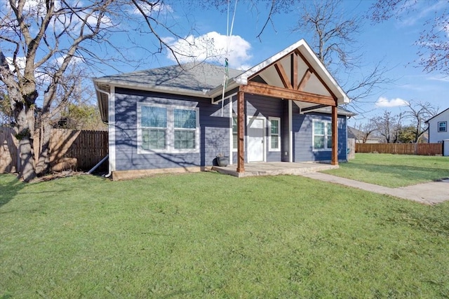 view of front of house with roof with shingles, fence, and a front yard