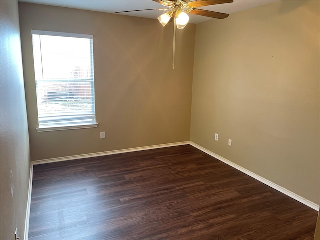 spare room with baseboards, dark wood finished floors, and a ceiling fan