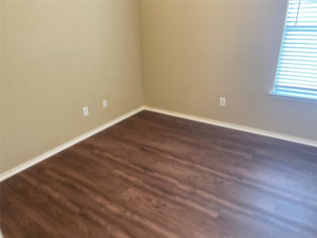 unfurnished room featuring baseboards and dark wood-type flooring