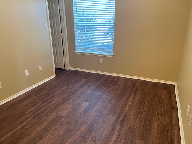 empty room featuring baseboards and dark wood-style flooring