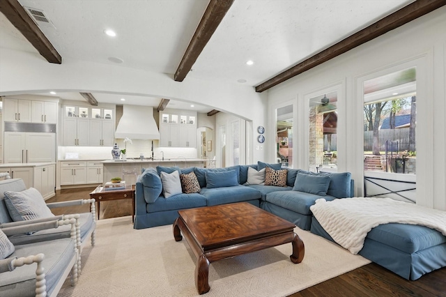 living room with arched walkways, beam ceiling, recessed lighting, visible vents, and wood finished floors