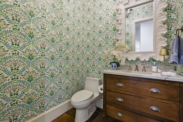 half bathroom with toilet, wallpapered walls, and vanity