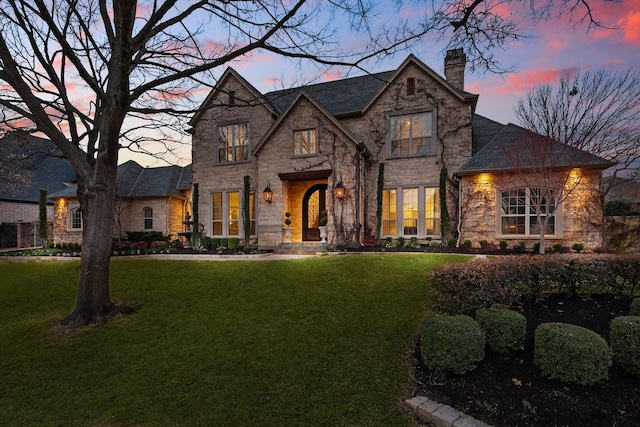 view of front of property featuring stone siding, a chimney, and a front lawn