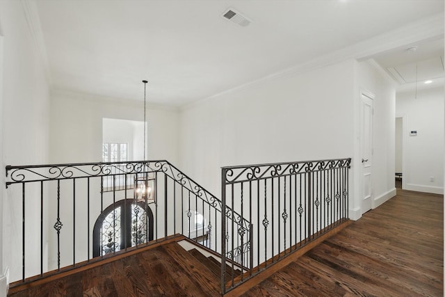 corridor featuring visible vents, attic access, ornamental molding, wood finished floors, and baseboards