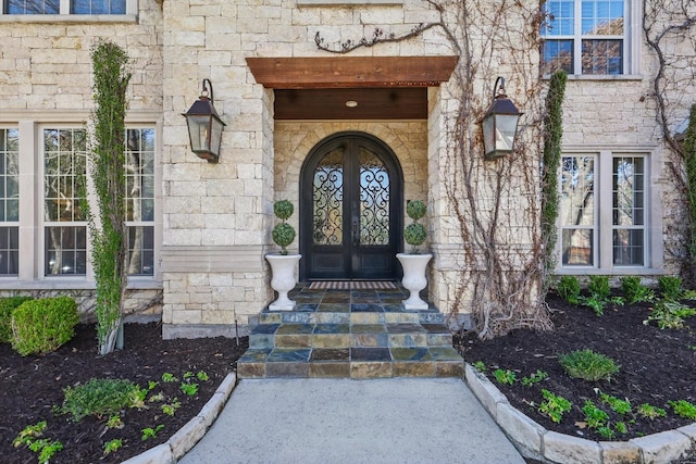 entrance to property featuring stone siding and french doors