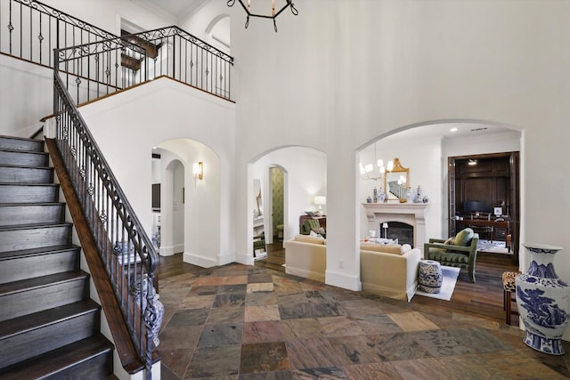 entryway featuring stone finish floor, a glass covered fireplace, a towering ceiling, and baseboards