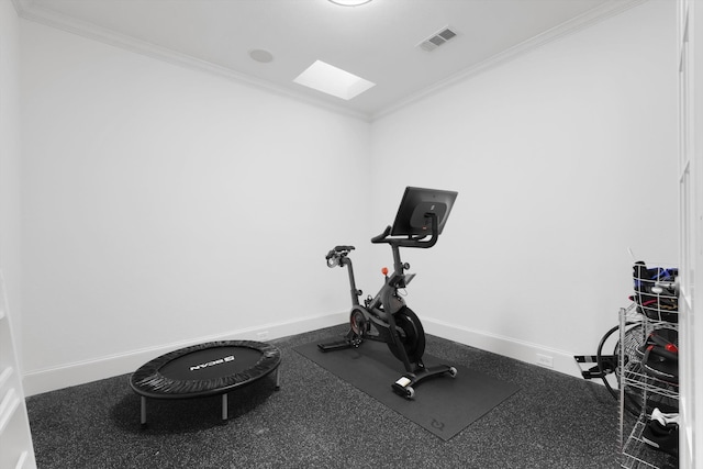 workout room with a skylight, baseboards, visible vents, and ornamental molding