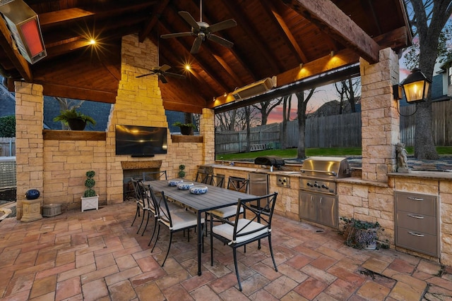 view of patio / terrace featuring area for grilling, fence, exterior kitchen, a gazebo, and an outdoor stone fireplace