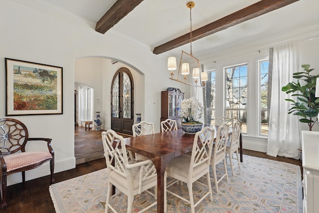 dining area featuring arched walkways, beam ceiling, wood finished floors, a chandelier, and baseboards