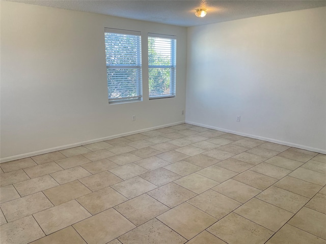 empty room featuring a textured ceiling and baseboards