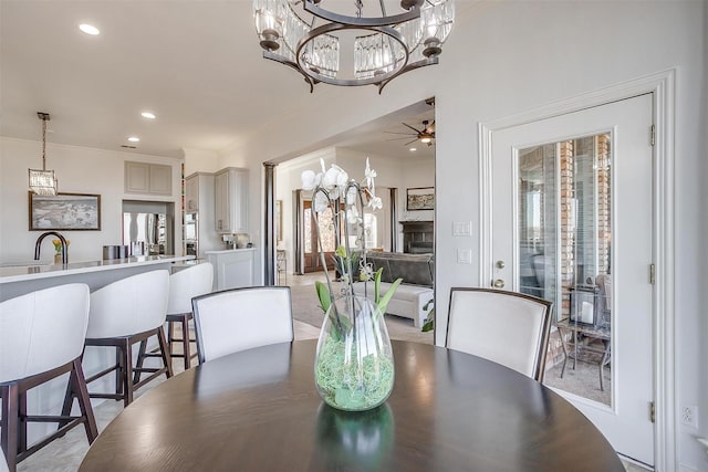 dining area with ceiling fan with notable chandelier, crown molding, and recessed lighting