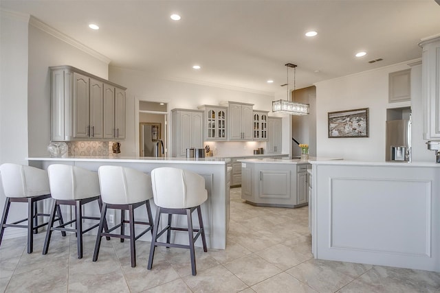 kitchen featuring visible vents, crown molding, a peninsula, and a kitchen bar