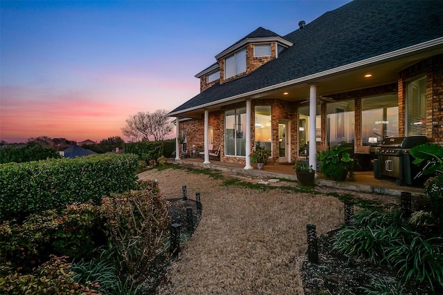 back of property at dusk with a shingled roof