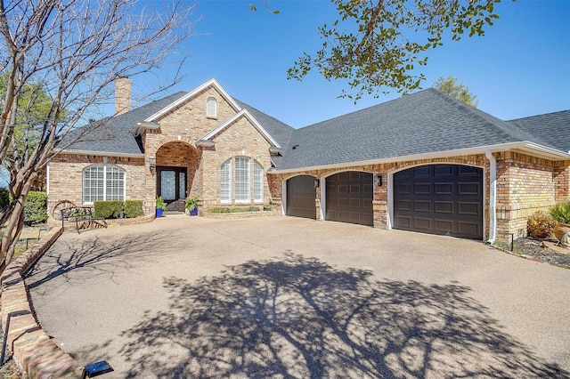 view of front of property with an attached garage, a shingled roof, a chimney, and brick siding