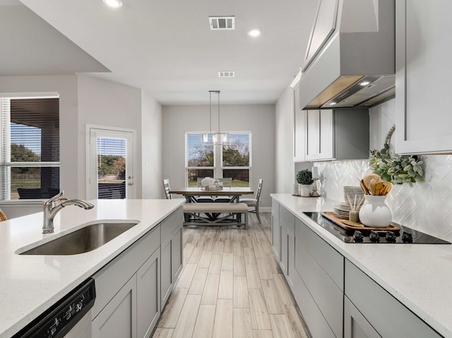 kitchen featuring black electric cooktop, premium range hood, a sink, visible vents, and stainless steel dishwasher