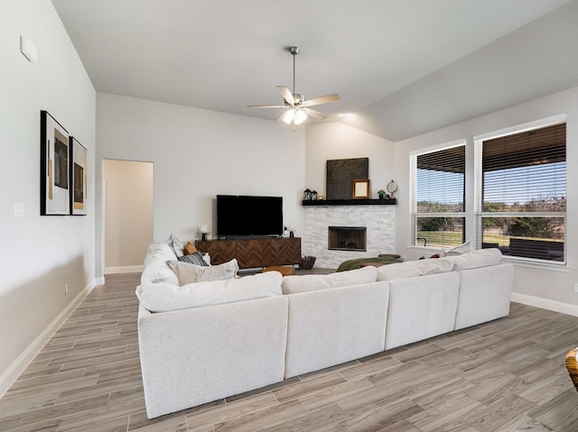 living area with a fireplace, light wood-style floors, vaulted ceiling, ceiling fan, and baseboards