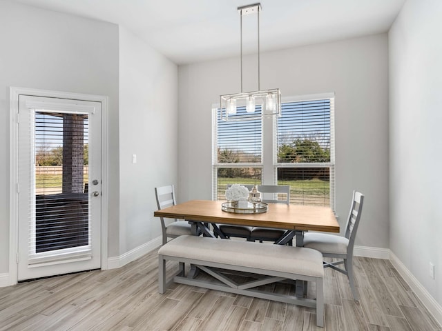 dining room with a chandelier, light wood-style flooring, and baseboards