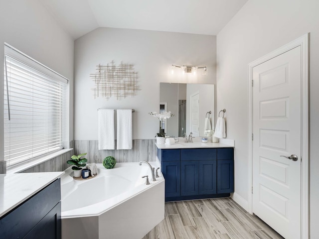 full bath featuring a shower, wood finished floors, vaulted ceiling, vanity, and a bath