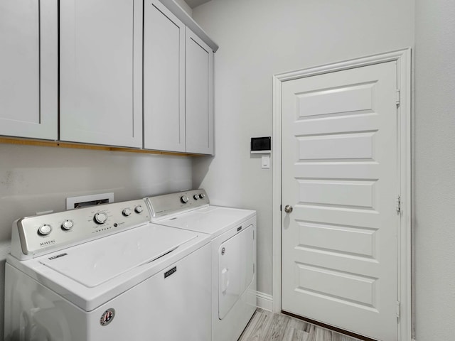 laundry area with cabinet space, light wood-style flooring, baseboards, and washer and dryer