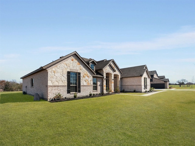 french provincial home with stone siding, brick siding, and a front lawn