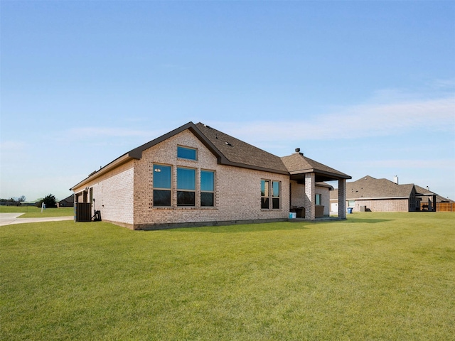 back of house featuring central air condition unit, a yard, and brick siding