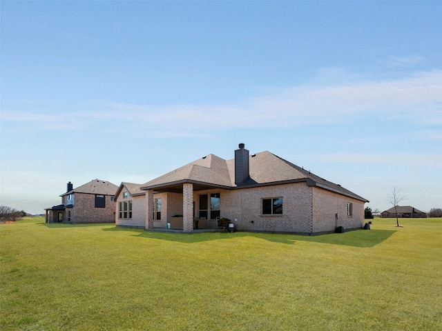 rear view of property with a yard, brick siding, and a chimney