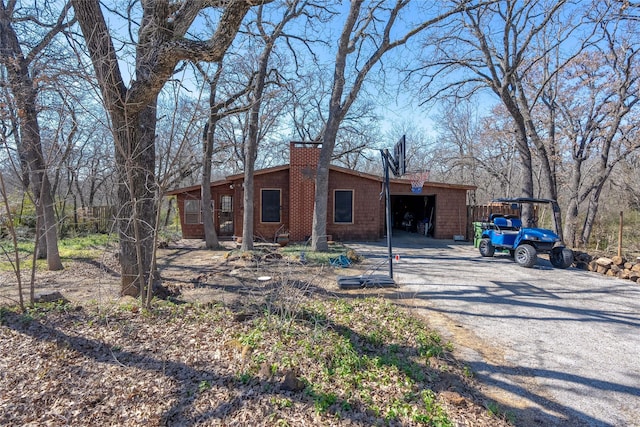 view of front of house with a garage, a chimney, and gravel driveway