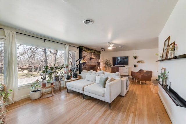 living area with ceiling fan, light wood finished floors, visible vents, and baseboards