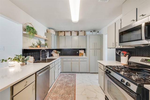 kitchen featuring marble finish floor, stainless steel appliances, a sink, and light countertops