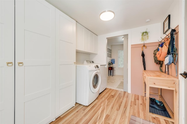 washroom featuring washer / clothes dryer, cabinet space, and light wood-style floors