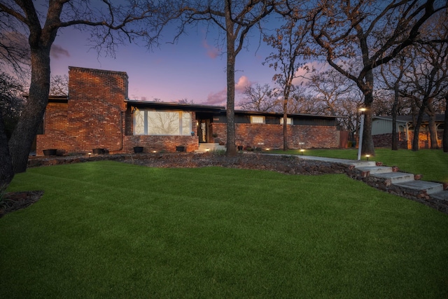 mid-century inspired home featuring crawl space, brick siding, a lawn, and a chimney