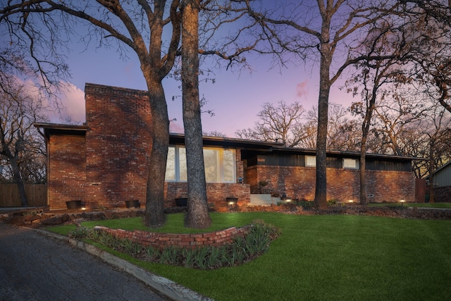 view of front of house with brick siding, a chimney, and a front yard