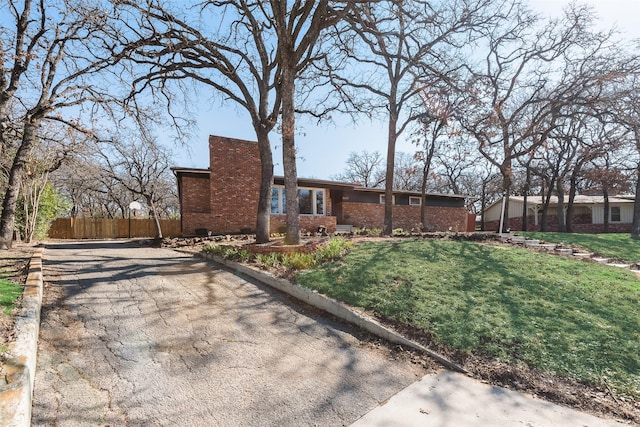 view of front of property with a chimney, fence, a front lawn, and brick siding