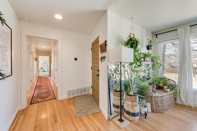 corridor featuring light wood-style floors, recessed lighting, visible vents, and baseboards