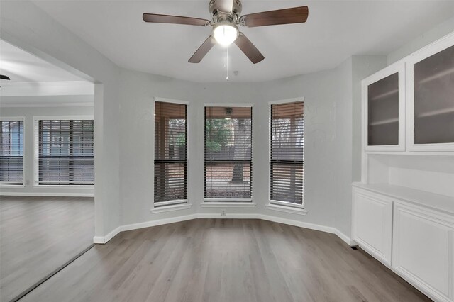 unfurnished dining area featuring ceiling fan, wood finished floors, and baseboards