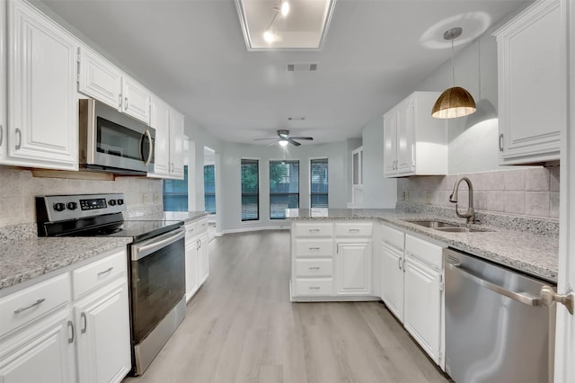 kitchen with a sink, white cabinetry, appliances with stainless steel finishes, light wood-type flooring, and decorative backsplash