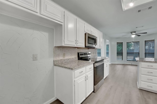 kitchen with light stone counters, light wood-style flooring, stainless steel appliances, visible vents, and tasteful backsplash