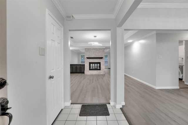 tiled entrance foyer with a fireplace, baseboards, and crown molding