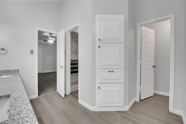 hallway with a sink, light wood-style flooring, and baseboards