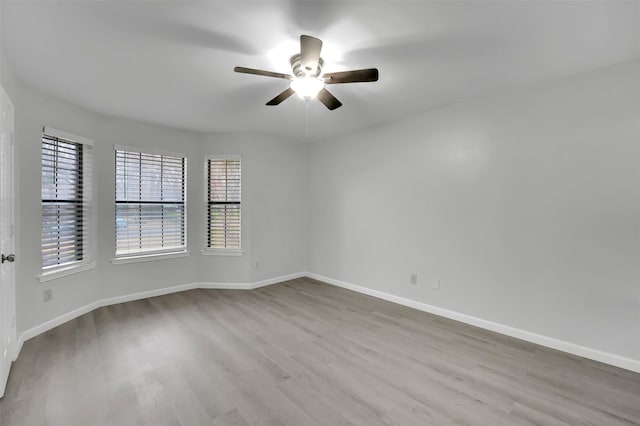 empty room featuring wood finished floors, a ceiling fan, and baseboards